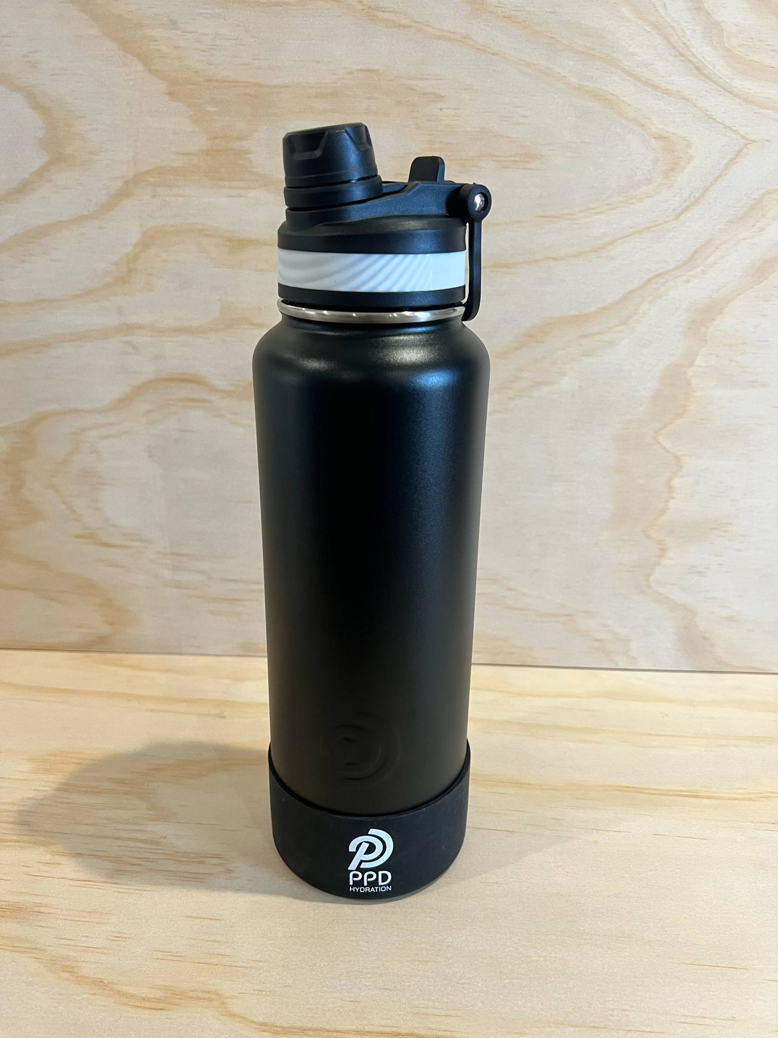 Black water bottle with a PPD logo on a wooden surface