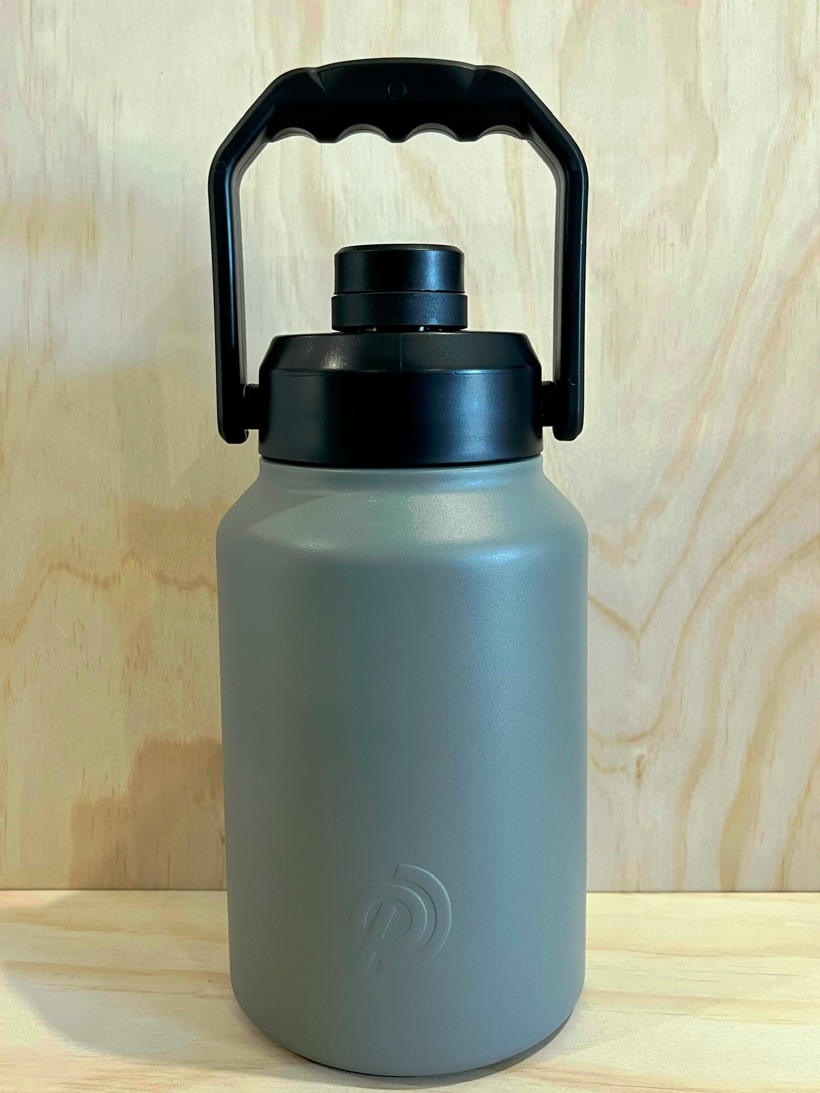 Gray water bottle with black lid and handle on a wooden background
