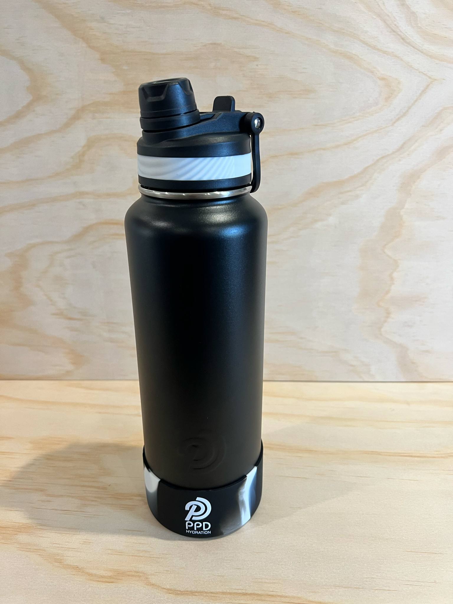 Black water bottle with PPD logo on a wooden surface
