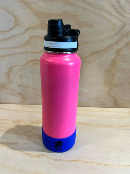 Pink water bottle with black cap and blue base on a wooden surface