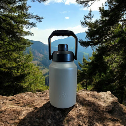 White water bottle with black lid on a rock with a mountainous landscape in the background
