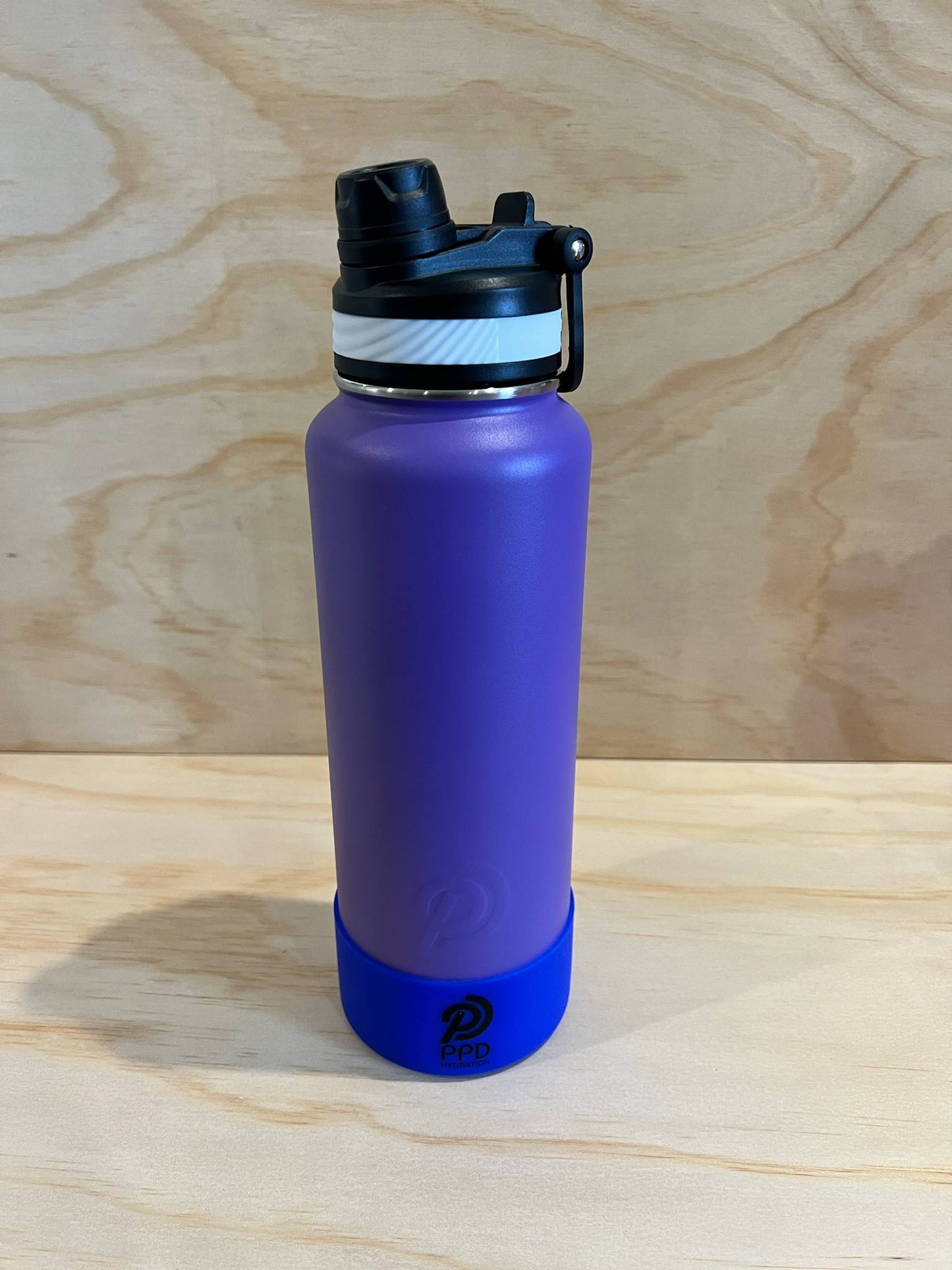 Purple water bottle with a black lid on a wooden surface