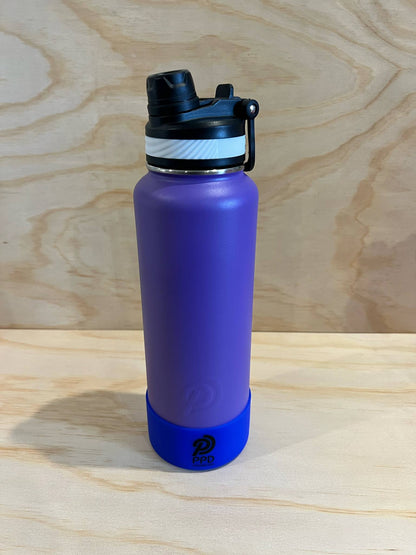 Purple water bottle with a black lid on a wooden surface