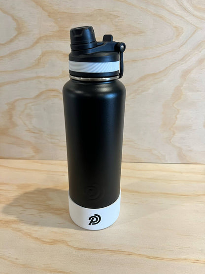 Black water bottle with white base on a wooden surface