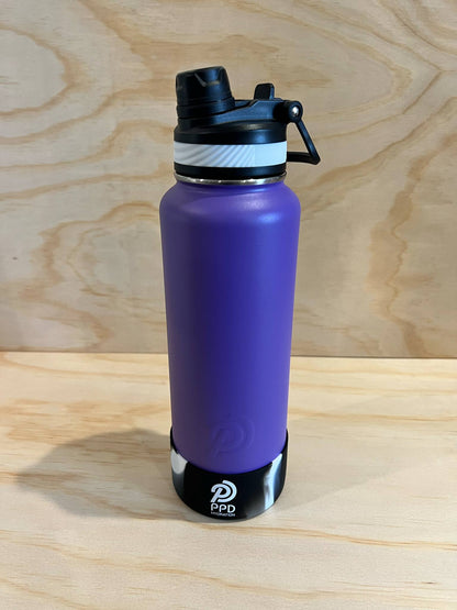 Purple water bottle with black cap on a wooden surface