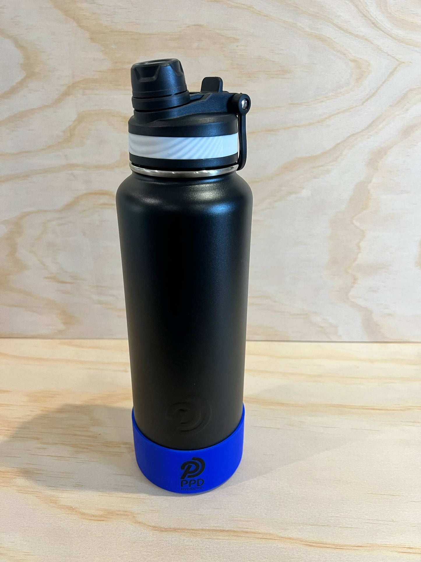 Black water bottle with blue base on a wooden surface