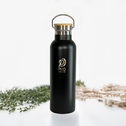 A black stainless steel insulated water bottle with a bamboo lid and a handle at the top. The bottle has a logo printed on it and is displayed alongside a bamboo bumper.