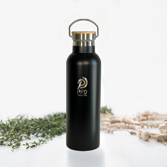 A black stainless steel insulated water bottle with a bamboo lid and a handle at the top. The bottle has a logo printed on it and is displayed alongside a bamboo bumper.