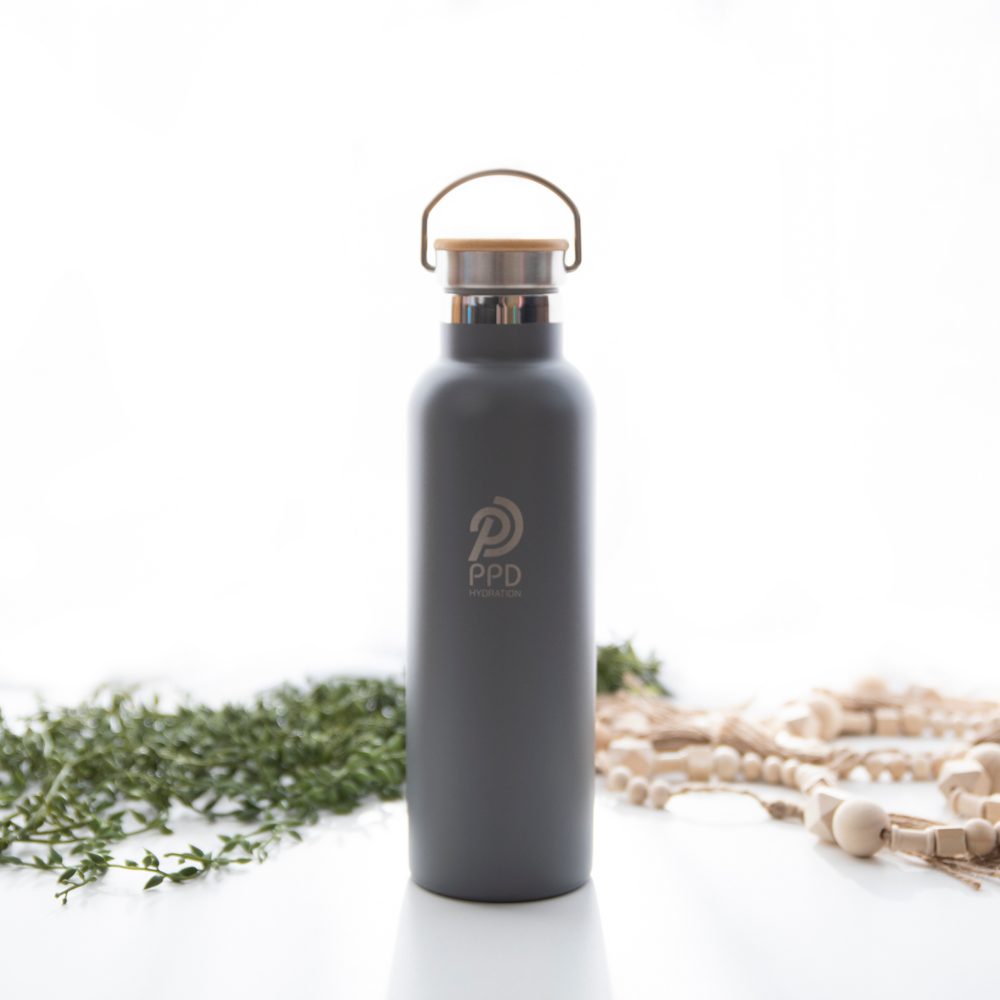 A gray stainless steel insulated water bottle with a bamboo lid, handle at top, and logo on the front. It is displayed with a white background and has a capacity of 750ml (25 oz).